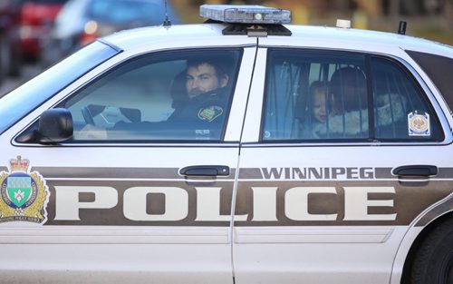 A woman and children sit in the back of a Winnipeg Police cruiser on Keenlyside Street at a standoff, Sunday, October 25, 2015. (TREVOR HAGAN / WINNIPEG FREE PRESS)