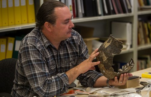Kevin Brownlee, curator of archeology at Manitoba Museum, examines an artifact on one of the lab tables. 150922 - Wednesday, September 23, 2015 -  MIKE DEAL / WINNIPEG FREE PRESS