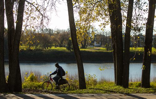 A cyclist rides on the path along Waterfront Drive while the Red River flows along early in the morning. 151006 - Tuesday, October 06, 2015 -  MIKE DEAL / WINNIPEG FREE PRESS