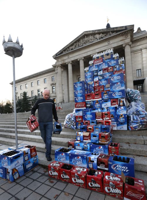 Angelo Mondragon, president of the Rural Hotel Owners of Manitoba assembles a throne of beer cases in front of the Manitoba Legislative Bld. Monday morning to protest the province's role in the decline of rural hotels.Bill Redekop  story. Wayne Glowacki / Winnipeg Free Press October 26 2015