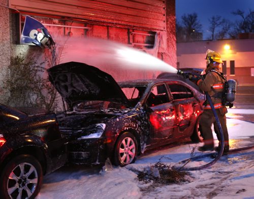 A Winnipeg Fire Fighter hoses down the melted sign of Nepon Auto Body shop on Dufferin Ave. at Salter St. after a car parked beside the building caught fire Tuesday morning. Wayne Glowacki / Winnipeg Free Press October 27 2015