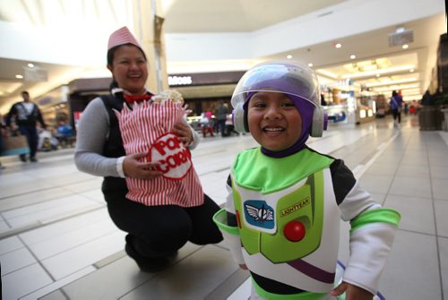 Three and a half year old Brent Linsangin  dressed as Buzz light years is all smiles after collecting goodies at Kildonan Place Mall with his mom Aileen Linsingan at the mall's annual Halloween event Friday.   Aileen Linsingan holds her 2 month old son, Brayden in the background   who is dressed as a bag of popcorn with her as the vendor, a costume she made after seeing it on Pinterest.   Standup photo Oct 29, 2015 Ruth Bonneville / Winnipeg Free Press