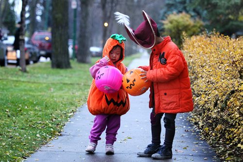 Six-year-old Dow Cha dressed as Captain Hook and his little sister Irene - 3yrs look into their pumpkin containers as they make their way down Wilton St. trick or treating on Halloween Saturday evening.  Standup photo Oct 31, 2015 Ruth Bonneville / Winnipeg Free Press