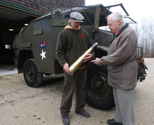 Veteran Stan Butterworth, 91 yrs, left, visits Rob Fast to see his restored 1943 Field Artillery tractor in his yard in Steinbach, Manitoba- Fast shows Butterworth a 17 lb armor piercing shell-See Bill Redekop story Nov 06, 2015   (JOE BRYKSA / WINNIPEG FREE PRESS)