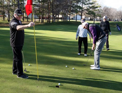 Jim Wood holds the flag for his buddy Bob Town on the 18th hole of Players Golf Course. Hundreds of people took to the course before Winter strikes Manitoba sometime soon. BORIS MINKEVICH / WINNIPEG FREE PRESS  NOV 9, 2015