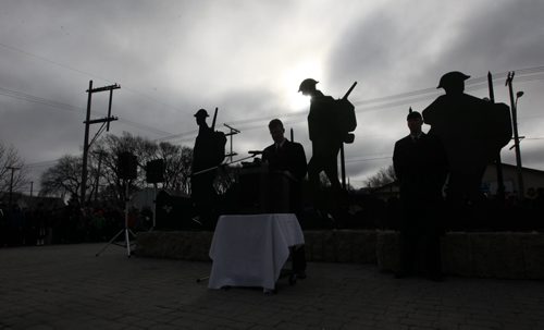 Andrew Swan, MLA Minto (centre), is silhouetted along with statues of three Valour Road Victoria Cross recipients. Sargeant-Major Frederick William Hall, Corporal Lionel B. Clarke and Lieutenant Robert Shankland, against the dark skies as he speaks to a large crowd gathered at Valour Road Commemorative Plaza  for Remembrance Day Service Wednesday.   Nov 11, 2015 Ruth Bonneville / Winnipeg Free Press