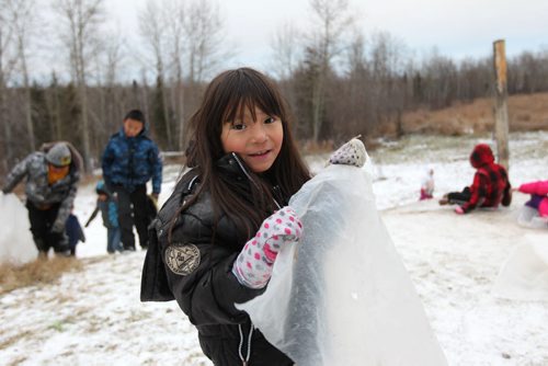 Photos for  Mary Agnes feature piece on CFS, Nelson House First Nation. Kids use scrap sheets of plastic to slide down a hill next to their home.   Nov 04, 2015 Ruth Bonneville / Winnipeg Free Press