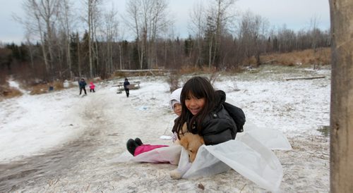 Photos for  Mary Agnes feature piece on CFS, Nelson House First Nation. Kids use scrap sheets of plastic to slide down a hill next to their home.   Nov 04, 2015 Ruth Bonneville / Winnipeg Free Press