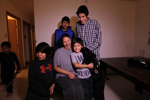 Photos for  Mary Agnes feature piece on CFS, Nelson House First Nation. Shirley Swanson, who at one time had her kids apprehended is now a inspiration to other mothers in the community after getting her life back on track and her kids back.  Photos of her with 4 of her 5 boys in their home in Nelson House. See story on how Nelson House Family and Community Wellness Centre is helping the community.   Names: Shirley Swanson with her youngest son Zacheus (grey), Silus (black), Nathan (blue) and Angus (plaid), Boy walking on left is cousin - DJ.  Her middle son, Phillip, not in photo.   Nov 04, 2015 Ruth Bonneville / Winnipeg Free Press