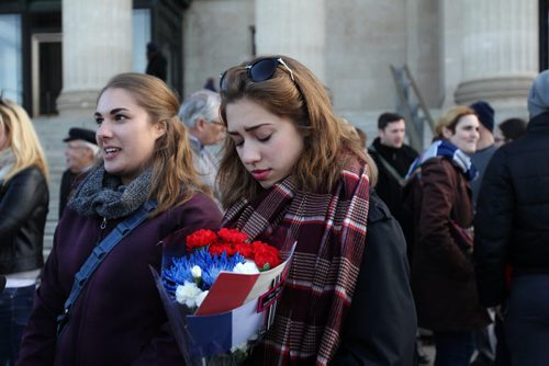 Mairin Douglas (right) and her sister Tingley brought a bouquet of red, white and blue flowers along with a French Flag to the Manitoba legislature Saturday afternoon to a vigil to honour those killed and hurt in the recent Paris attacks.  Both girls had recently lived in France on exchange trips developed close relationships with friends living there. See Kevin Rollason's story.    Nov 14, 2015 Ruth Bonneville / Winnipeg Free Press