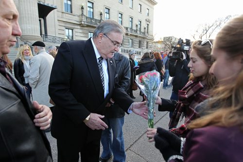 French Honourary Consul Bruno Burnichon is handed a bouquet of red, white and blue flowers along with a French Flag from Mairin Douglas and her sister Tingley  after  vigil for Paris attacks  Saturday afternoon at the legislature.  Both girls had recently lived in France on exchange trips and wanted to come out and support community.   See story.  Nov 14, 2015 Ruth Bonneville / Winnipeg Free Press