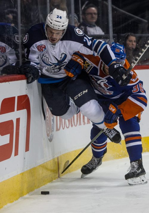 Manitoba Moose' Scott Kosmachuk (24) takes to the air while being check by Bakersfield Condors' Josh Currie (36) during second period AHL action at MTS Centre Sunday afternoon. 151122 - Sunday, November 22, 2015 -  MIKE DEAL / WINNIPEG FREE PRESS
