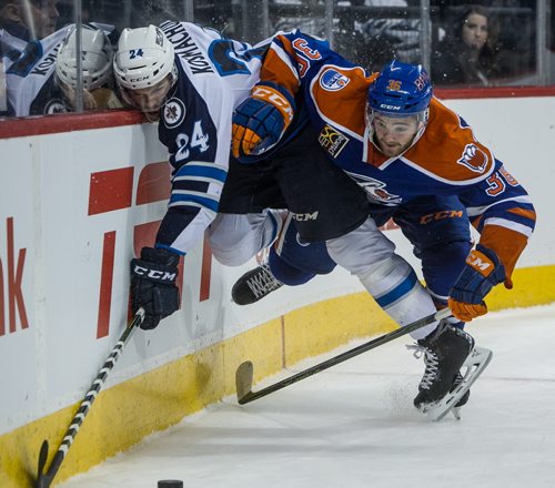 Manitoba Moose' Scott Kosmachuk (24) takes to the air while being check by Bakersfield Condors' Josh Currie (36) during second period AHL action at MTS Centre Sunday afternoon. 151122 - Sunday, November 22, 2015 -  MIKE DEAL / WINNIPEG FREE PRESS