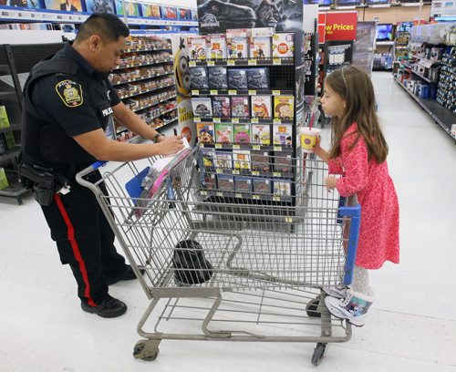 Over 60 Winnipeg Police Service officers took on a role of personal shopper at St Vital Centre today. Armed with Christmas wish lists, the officers were paired up with 60 specially chosen children as part of CopShop.- St. Vital Centre and the WPS along with Louis Riel, Winnipeg One, River East Transcona, St. James-Assiniboia, Division Scolaire franco-manitobaine (Franco-Manitoban School Division) and Pembina Trails School Divisions are joining forces again for CopShop during which each child will receive a $200 gift card donated by St. Vital Centre.- Const Orlando Buduhan  checks list and pushes Julie  Kingdon, 7yrs, from General Vanier  School around Walmart-Standup PhotoNov 25, 2015   (JOE BRYKSA / WINNIPEG FREE PRESS)