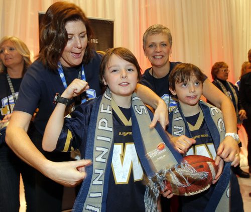 CFL AWARDS RED CARPET EVENT AT CLUB REGENT - Fans and players get to mingle. Some kids get some free scarfs as they enter the event.The kids are brothers Mathieu (l) and Eric (r) Nanka. The adults putting them on them are L-R Rachel Jones and Chrisine Girardin.  BORIS MINKEVICH / WINNIPEG FREE PRESS  NOV 26, 2015