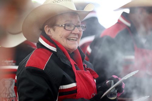 Faye Drinnan with the Calgary Grey Cup committee is all smiles as she cooks sausages to go with the free pancake breakfast in the U of W's street festival tent  during the 103rd Grey Cup Festival activities  Saturday.  Standup Nov 28, 2015 Ruth Bonneville / Winnipeg Free Press