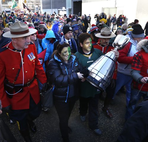 Rob Antonello and Sonya Siume take a turn carrying the Grey Cup on the Fan March to The Forks.  Geoff Kirbyson  story.Wayne Glowacki / Winnipeg Free Press Nov. 29    2015