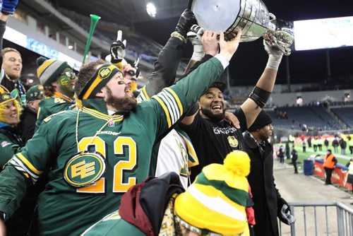 Edmonton Eskimo fans reach to touch the cup as team member bring it into the stands while  celebrating their teams win at the 103rd  Grey Cup against  Ottawa Redblacks  at Investors Group Stadium in Winnipeg on Sunday, Nov. 29, 2015.  Nov 29, 2015 Ruth Bonneville / Winnipeg Free Press