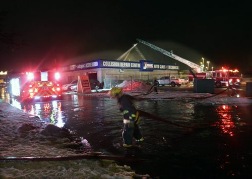 Firefighters wade through deep water to salvage hoses at scene of fire at the JMax Auto Service at Lorette and Pembina near 645 am Tuesday- The fire started near 1130 PM Monday night- crews have been battling since- See storyNov 30, 2015   (JOE BRYKSA / WINNIPEG FREE PRESS)