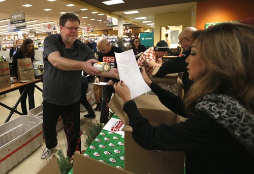 At left, Free Press columnist Doug Speirs and Tracy Koga with Shaw TV compete in the media challenge to fill the list for a 3 person hamper as quickly as possible.  This event was to highlight the Christmas Cheer Board  grocery donation Safeway paper bag delivered in the Winnipeg Free Press to homes in Winnipeg Tuesday. People can fill up the paper bags with non-perishables or purchase $5 and $10 care packages and the Safeway store will take them to the Cheer Board. Doug Speirs  story Wayne Glowacki / Winnipeg Free Press Dec.1 2015