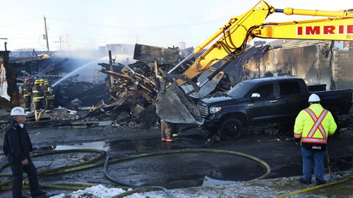 A demolition company excavator was dragging out  damaged vehicles Tuesday afternoon that were parked in the JMax Auto Centre on Pembina Hwy. the building caught fire Monday night. Wayne Glowacki / Winnipeg Free Press Dec.1 2015