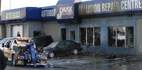 Tow trucks were removing damaged vehicles Tuesday afternoon that were parked in or by the JMax Auto Centre on Pembina Hwy. the building caught fire Monday night. Wayne Glowacki / Winnipeg Free Press Dec.1 2015