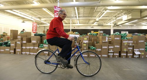 Cheer Board assistant executive director Linda Grayston puts her vintage bike to use as she does her daily work in the spacious warehouse. Interlake grade 5-7 students from Balmoral Schools Social Justice Group came into Winnipeg on Dec. 3 to pitch in filling food hampers at the Christmas Cheer Board. Groups of school kids are now coming to the Cheer Board every day to help out loading up some of the approximately 19,000 hampers that will be given out this holiday season. Photo by Jason Halstead/Winnipeg Free Press RE: Social Page