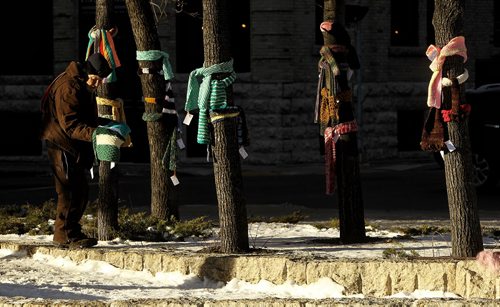 Brad Hollingsworth checks out the scarves left by the Chase the Chill group at Old Market Square Sunday morning. The group made around 700 scarves and left them in the Exchange District for anyone to take.  151206 December 06, 2015 Mike Deal / Winnipeg Free Press
