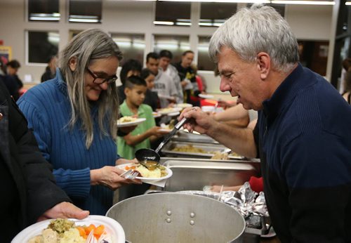 West End resident Audrey (left) gets some gravy from volunteer server Grant Platts at the West End Cultural Centres annual holiday dinner and concert on Dec. 9, 2015. Over 150 west-central area residents enjoyed a full turkey dinner with all the fixings, live music and a visit from Santa to hand out gifts to the kids. Photo by Jason Halstead/Winnipeg Free Press RE: Social Page