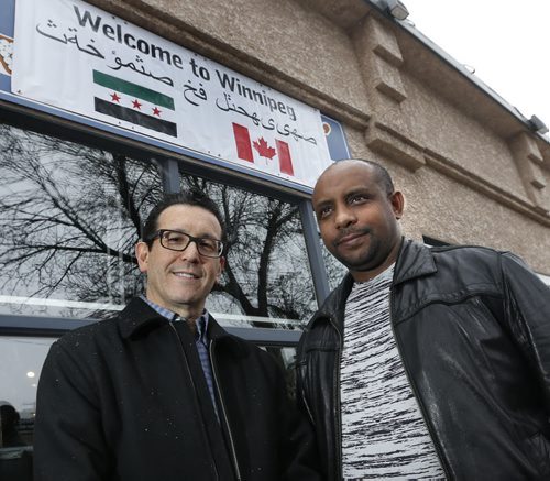 At left, Sal Infantino owner of X-Cues Billiards and Café on Sargent Ave. with the Welcome to Winnipeg sign in Arabic in front of his business along with customer Amare Gebru will be welcoming newcomers to the West End.  Carol Sanders story   Wayne Glowacki / Winnipeg Free Press Dec. 10   2015