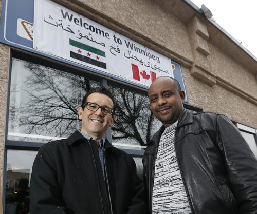 At left, Sal Infantino owner of X-Cues Billiards and Café on Sargent Ave. with the Welcome to Winnipeg sign in Arabic in front of his business along with customer Amare Gebru will be welcoming newcomers to the West End.  Carol Sanders story   Wayne Glowacki / Winnipeg Free Press Dec. 10   2015