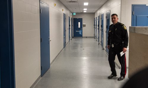 A tour of the new Winnipeg Police Service Headquarters at 245 Smith Street. Public Information Officer Jason Michalyshen walks past the desk in the Central Processing Unit where prisoners are brought before being taken to a holding/interview room (background). 151214 - Monday, December 14, 2015 -  MIKE DEAL / WINNIPEG FREE PRESS