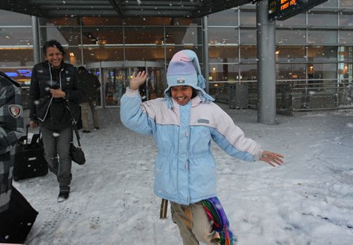 Eight-year-old Gianna Dinzey from Trinadad is elated as she experience's snow for the first time in their lives after arriving at the Wpg airport Wednesday with their dad to visit family here in Wpg for Christmas.  Her aunt Ave Dinzey smiles as she walks behind her.  Standup photo  Dec 16, 2015 Ruth Bonneville / Winnipeg Free Press