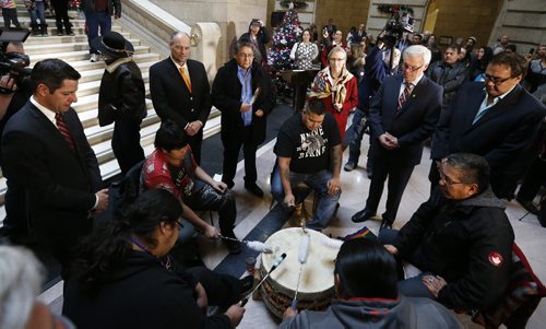 At the Manitoba Legislature in Winnipeg today, Thursday, December 17, 2015 (L to R) City of Winnipeg mayor Brian Bowman, Manitoba minister Drew Caldwell, Chief Erwin Redsky, Shoal Lake No.40 First Nation, Carolyn Bennett, Minister of Indigenous and Northern Affairs, Manitoba,  Premier Greg Selinger, , and Manitoba Minister Eric Robinson stand around drummers during an announcement of an intergovernmental partnership that will benefit the First Nation by building a 24 km road from the community to the Trans Canada Highway.   THE CANADIAN PRESS/John Woods