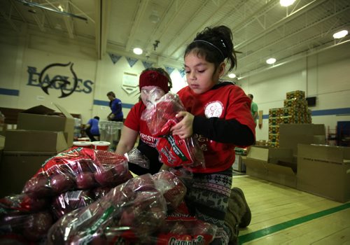 Eight-year-old Kaelyn Smith helps out packing hampers  at R.B. Russell School Saturday with her mom, Jody Voss.  LOCAL COMPANIES AND COMMUNITY VOLUNTEERS FILL CHRISTMAS HAMPERS WITH TURKEYS, TOYS AND HOLIDAY CHEER FOR ABORIGINAL FAMILIES with the joint forces of MTS and Ma Mawi Wi Chi Itata Centre Saturday, December 19, season for Aboriginal families in need.  Standup photo  Dec 18, 2015 Ruth Bonneville / Winnipeg Free Press