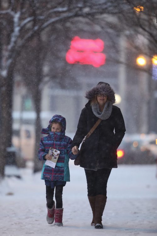 Pedestrians walk down Main Street during snowfall near City Hall, Saturday, December 19, 2015. (TREVOR HAGAN / WINNIPEG FREE PRESS)