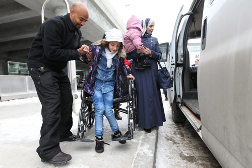Nicodemus Gezahegn with The Welcome House, helps one of the children of the Albakar family out of her wheelchair and into the waiting van at  the airport in Winnipeg  Saturday.  The Albakar family of eight, were headed to Welcome Place. See MA story.  Dec 19, 2015 Ruth Bonneville / Winnipeg Free Press