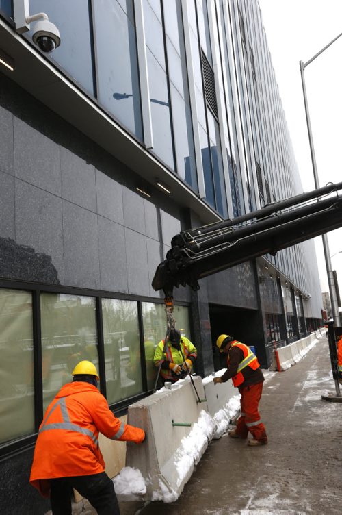 Crews install concrete security dividers by the the new police HQ along Smith St. Monday. Bart Kives story. Wayne Glowacki / Winnipeg Free Press Dec. 21  2015