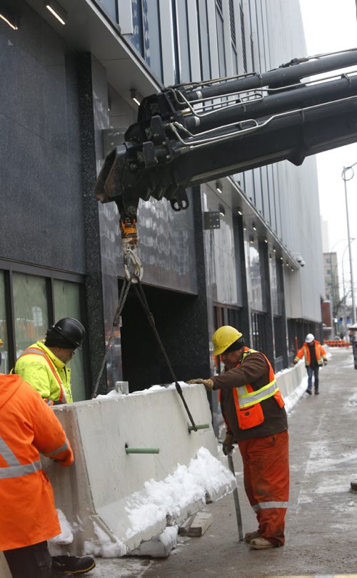 Crews install concrete security dividers by the the new police HQ along  Smith St. Monday. Bart Kives story. Wayne Glowacki / Winnipeg Free Press Dec. 21  2015