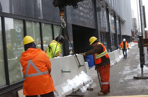 A crane lowers a concrete security divider by the the new police HQ  along Smith St. Monday. Bart Kives story. Wayne Glowacki / Winnipeg Free Press Dec. 21  2015