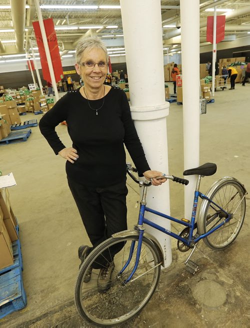 Linda Grayston the assistant executive director for the Christmas Cheer Board rides around the warehouse on a blue bike.  151221 December 21, 2015 MIKE DEAL / WINNIPEG FREE PRESS