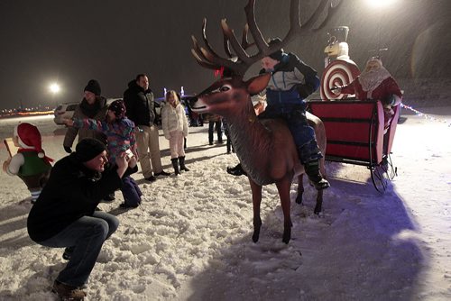 Families line up to snap a shot with Santa and Rudolf at the Canad Inns Winter Wonderland at the Red River Exhibition Park Tuesday night. The 2.5km drive features lighted christmas displays, a skating pond and an enclosed horse drawn sleigh ride, complete with built in fireplace. Admission for cars is $15 and ranges up to 45 passenger buses for $65. Deember 22, 2015 - (Phil Hossack / Winnipeg Free Press)
