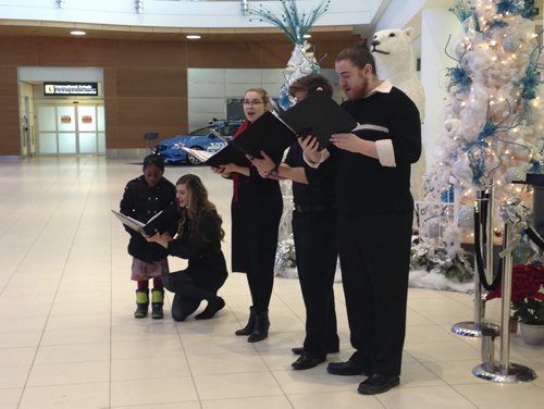 (l-r)Colleen Furlan, Amanda Stegmaier, Chad Abrahamson and Jay Janzen.   Travellers got a warm welcome at the Winnipeg airport today with carollers from the University of Manitoba Singers serenading them as they arrived and greeted friends and family members. Colleen Furlan is singing with 6-year-old Abigail Adebowale, who is visiting from the UK with her family.   December 24/2015 Leah Hansen/Winnipeg Free Press