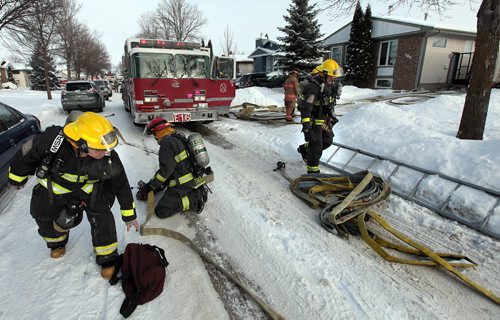 City Fire crews pick up their tools after clearing smoke from a home at 165 Tiberland Lanein the city's northern end. A faulty furnace fan was the sourse of the smoke and firefighters were abble to prevent further damage. Eight residents of the home were examined at the scene for smoke inhalation but not transported to hospital. December 25, 2015 - (Phil Hossack / Winnipeg Free Press)
