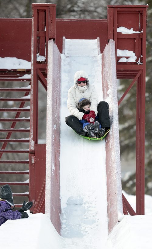 Laurie Boutin and her son Olivier (2) zoom down the toboggan slide enjoying a frosty Christmas morning in Kildonan Park.Sister Juliette (7) cheers from the sidelines at the bottom of the slide.  Laurie and her family are visiting her parents in the city while back at their Toronto home golfers are enjoying +15C WEATHER. December 25, 2015 - (Phil Hossack / Winnipeg Free Press)