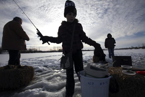 Nine-year-old Ashley Patenaude learns to Ice Fish for the first time at FortWhyte Alive's Family Fun Ice fishing event Tuesday afternoon with her family.  Even though the top layer of ice was slushy the ice is thick and safe to walk on for outdoor activities at the centre such as tobogganing, ice fishing and snow shoeing.     Standup Dec 29, 2015 Ruth Bonneville / Winnipeg Free Press