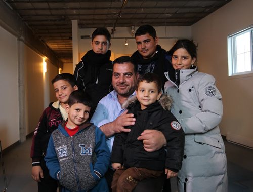 Portrait of Syrian family living in central Winnipeg.  Dad is Khaled Alhmeidat, Samer (back row, left wt scarf 16yrs) Mohammad, Rania (the girl is 14) little brothers Moaiad (left blk & red), Motasem (blue) and Motaz (2). Eight total in family but only 7 in picture.   Missing: moms name is Eqbal. Theyre from Damascus and arrived in Winnipeg on Monday, Dec 27, 2015.   See Carol Sanders story.  Dec 30, 2015 Ruth Bonneville / Winnipeg Free Press