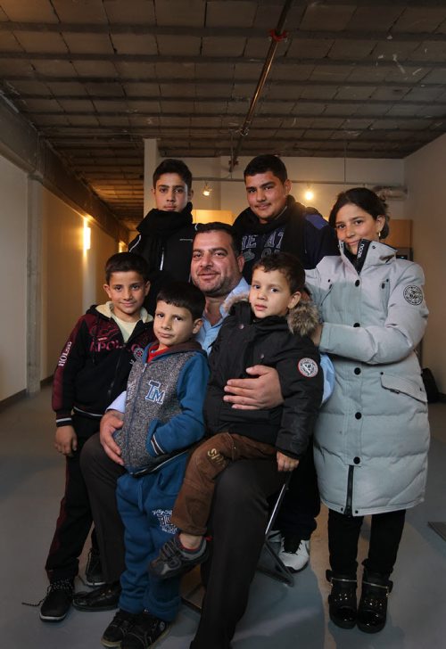 Portrait of Syrian family living in central Winnipeg.  Dad is Khaled Alhmeidat, Samer (back row, left wt scarf 16yrs) Mohammad, Rania (the girl is 14) little brothers Moaiad (left blk & red), Motasem (blue) and Motaz (2). Eight total in family but only 7 in picture.   Missing: moms name is Eqbal. Theyre from Damascus and arrived in Winnipeg on Monday, Dec 27, 2015.   See Carol Sanders story.  Dec 30, 2015 Ruth Bonneville / Winnipeg Free Press