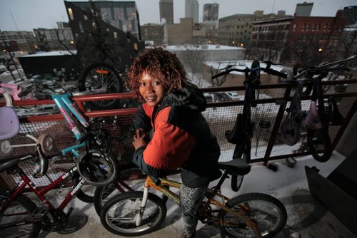 Musu Kayfay and her family ( two kids, a sister and sister-in-law) who arrived in March from Sierra Leone for Year of the Refugee 49.8. Winter was her biggest surprise, now she poses on her balcony with her son's bicycle. See Carol Sanders story. January 7, 2016 - (Phil Hossack - Winnipeg Free Press)