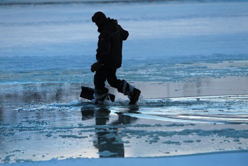 A Forks River Trail construction worker walks through water pumped onto the surface of the ice on the Red River Friday as crews work to create a smooth skating surface at the Forks.   Jan 08, 2016 Ruth Bonneville / Winnipeg Free Press
